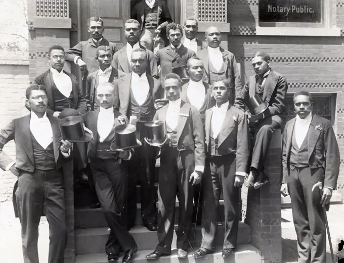 Law graduating class at Howard University, Washington DC. Sixteen African-American law students standing on steps of building, wearing formal attire, some holding top hats.