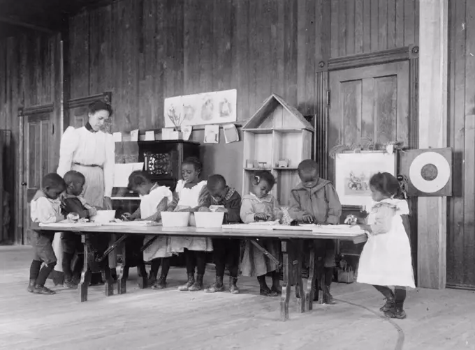 Eight African American children, in kindergarten, learning washing and ironing at Whittier Primary School, Hampton, Virginia 1900.