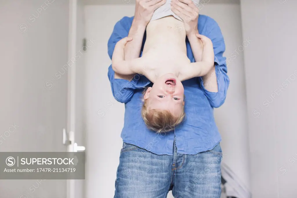 Father holding baby upside down