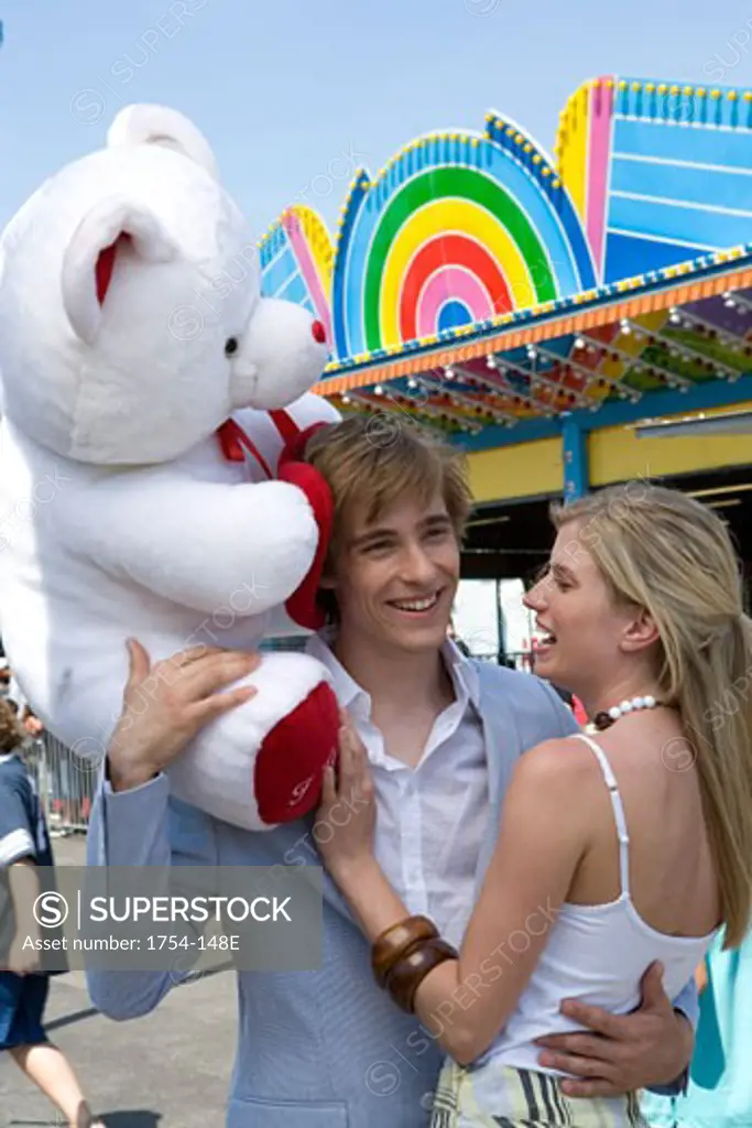 Young man holding a stuffed animal and embracing a young woman