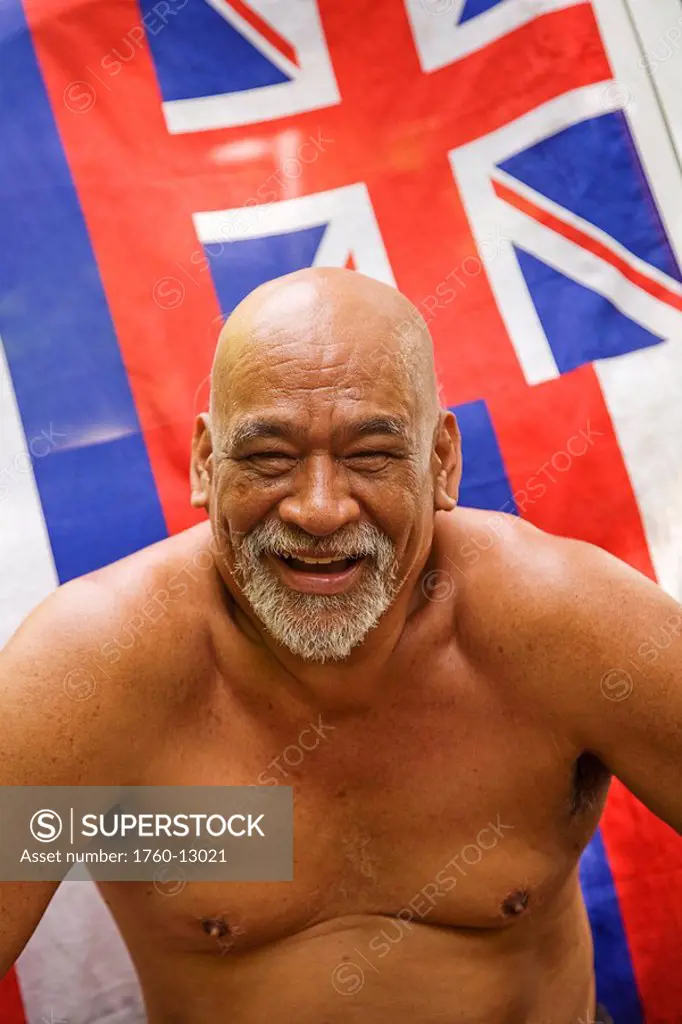 Hawaii, Maui, Local hawaiian man sitting in front of a Hawaiian Flag Soft Focus.