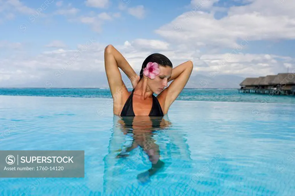 French Polynesia, Moorea, Woman relaxing in oceanside resort pool.