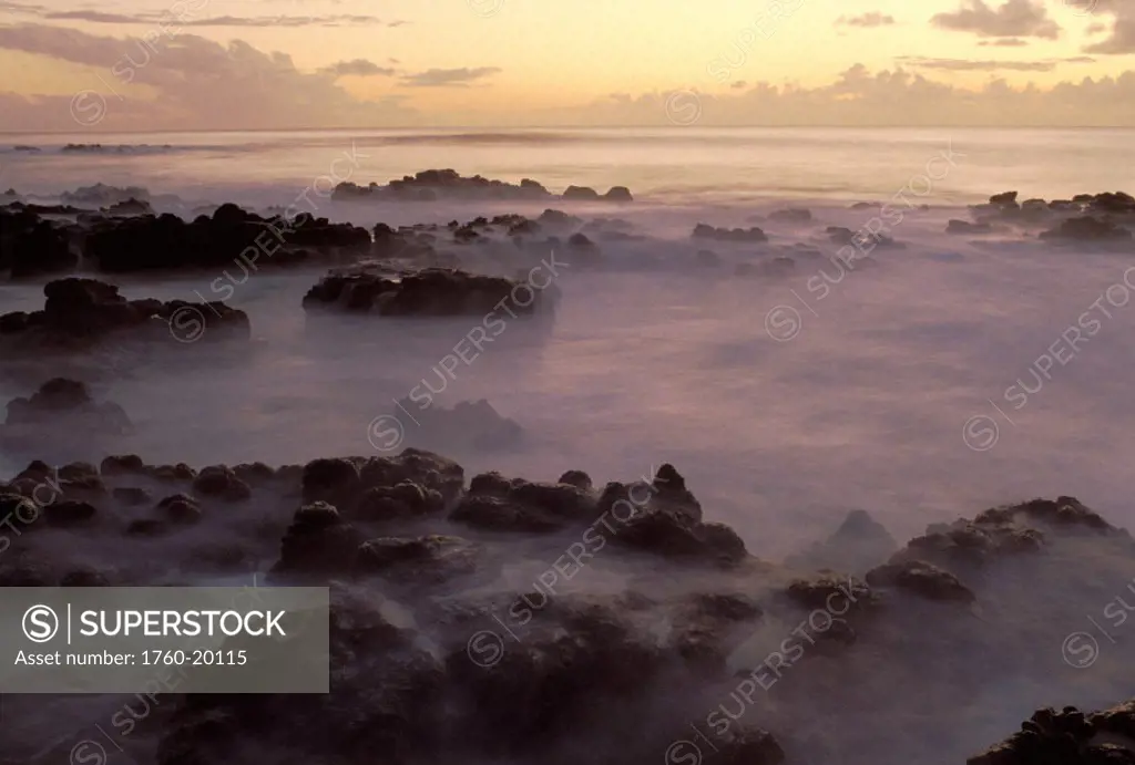 Hawaii, Molokai, Kau Poa beach, Lava rocks in foggy layer over pale sunrise water