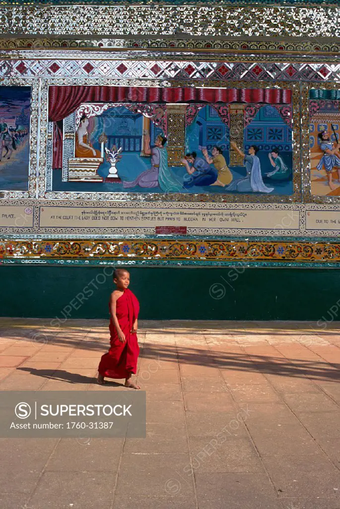 Myanmar, Burma view of monk walking by painted reliefs temple courtyard