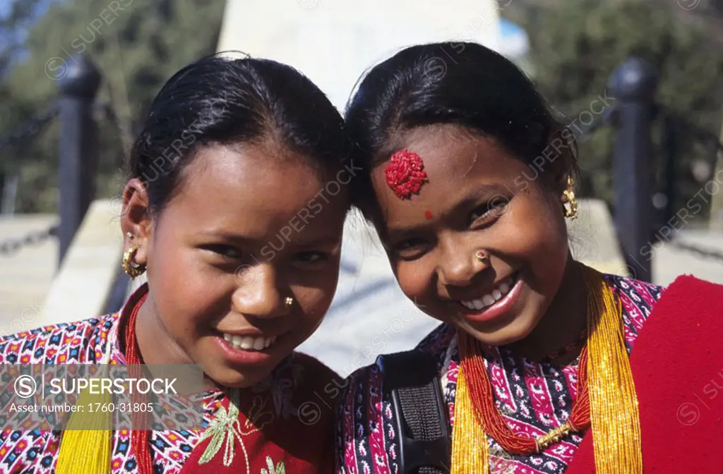 Nepal, Gorkha, portrait of two smiling local girls dressed in colorful apparel for festival.