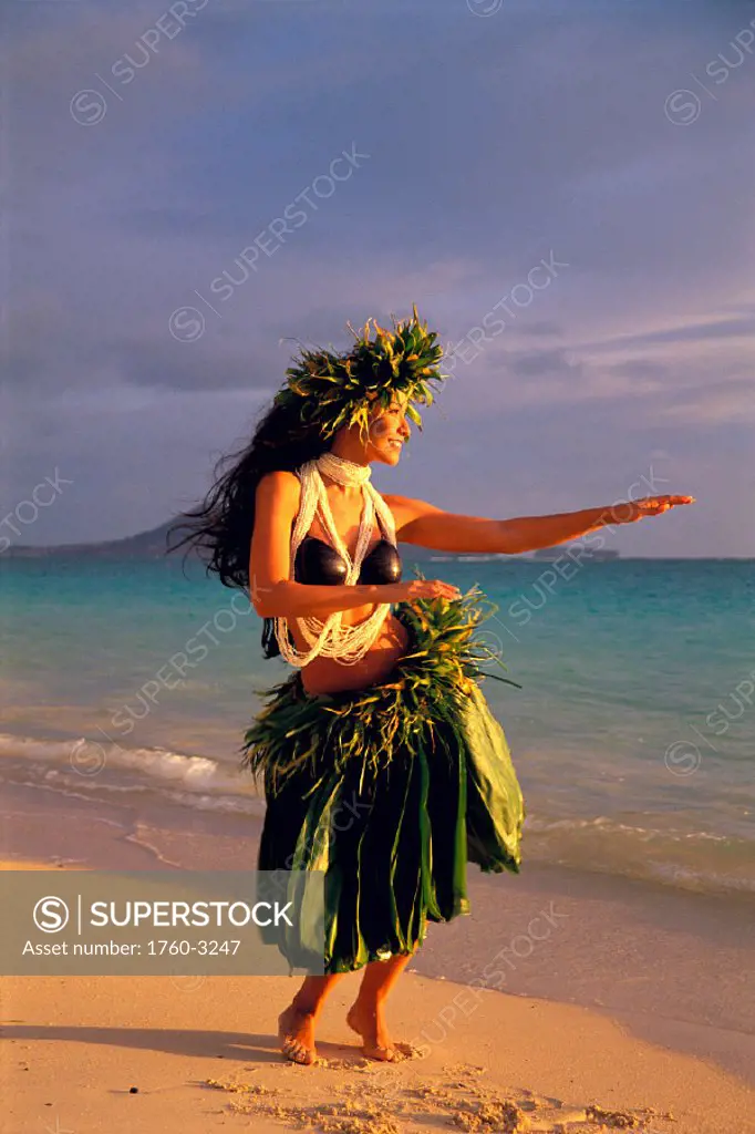 Young woman hula on beach @ sunrise w/ coconut top, haku ti leaf