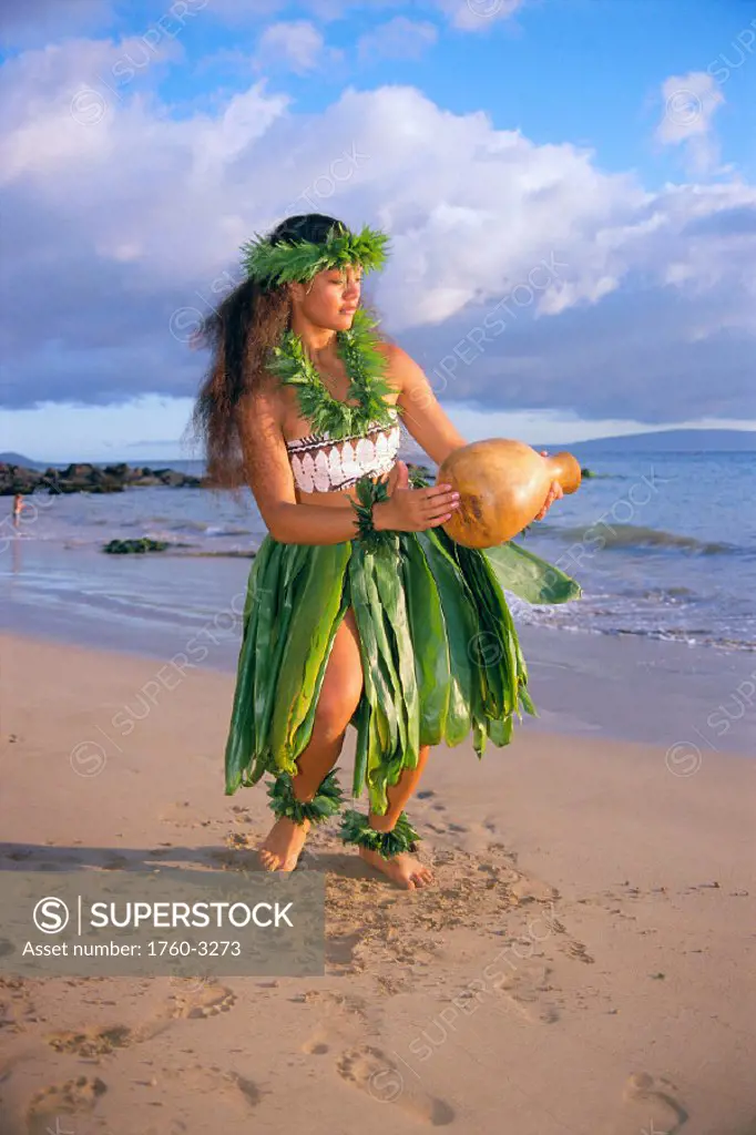 Woman hula on beach with ipu in hand, wearing ti leaf skirt & full set leis C1462