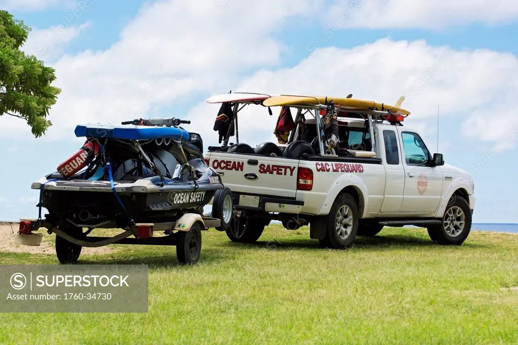 Lifeguard safety vehicles parked by the shore of Waimea Bay; Oahu, Hawaii, United States of America