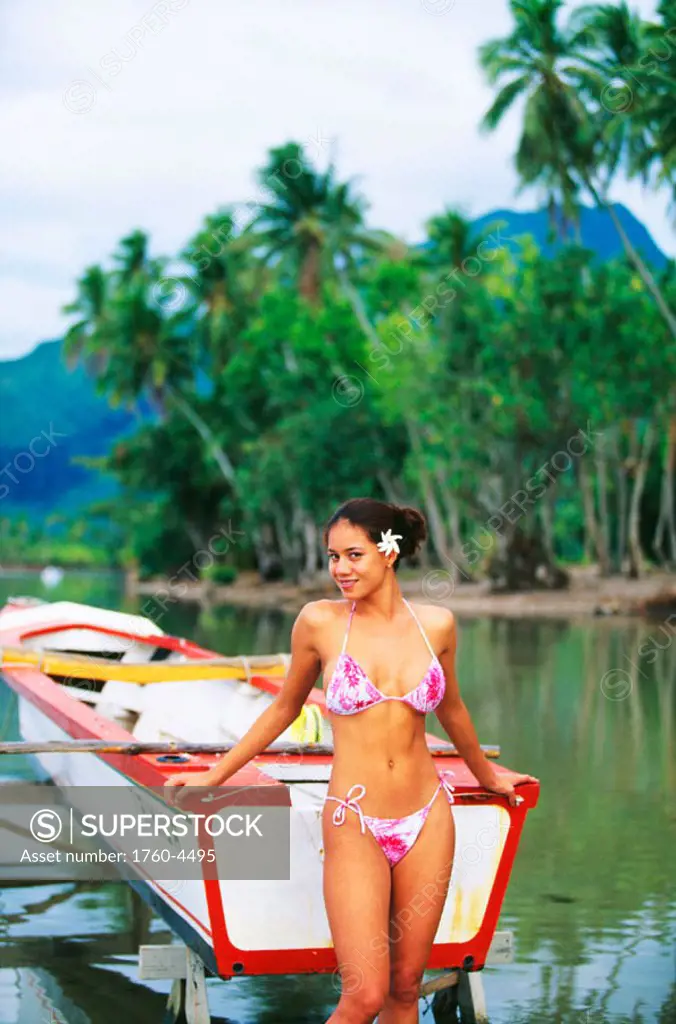 Tahiti, Sexy local girl standing by a lagoon holding onto a boat.