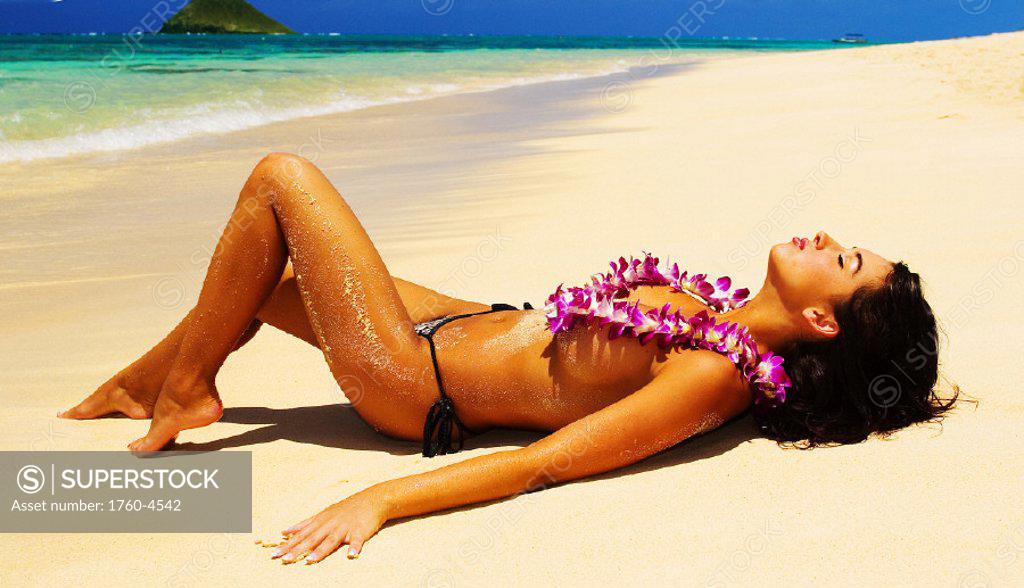 young woman in a bikini lounging on the beach in hawaii Stock
