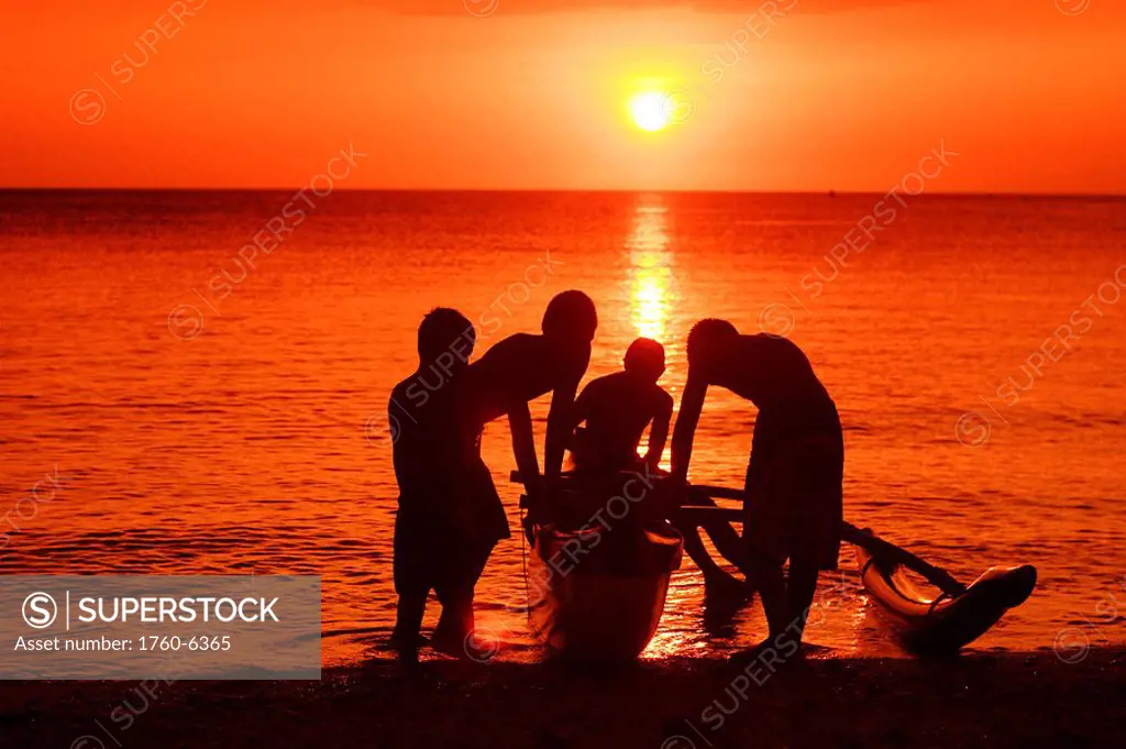 Hawaii, Oahu, North Shore, group of boys hold a canoe, silhouetted by bright orange sunset 