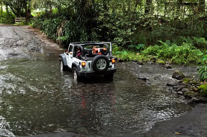 Tourist 4-wheel drive jeep crosses Waipio River in Waipio River Valley; Waipio, Oahu, Hawaii, United States of America