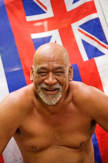 Hawaii, Maui, Local hawaiian man sitting in front of a Hawaiian Flag Soft Focus.