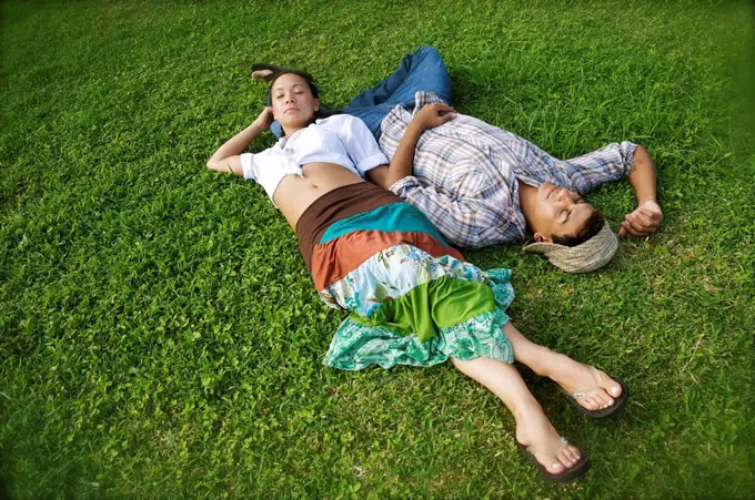 Hawaii, Kauai, North Shore, Young couple take a nap in grass.