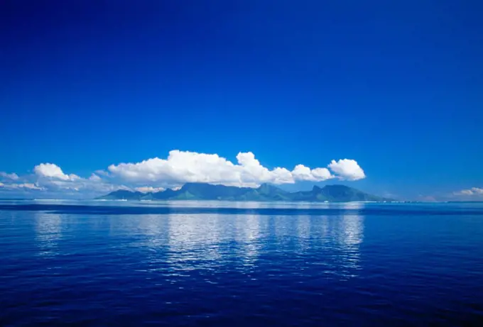 French Polynesia, Tahiti, Cumulus clouds over a calm ocean.