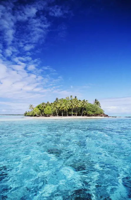 French Polynesia, Tahiti, Bora Bora, Motu Island in distance, turquoise water and blue sky.