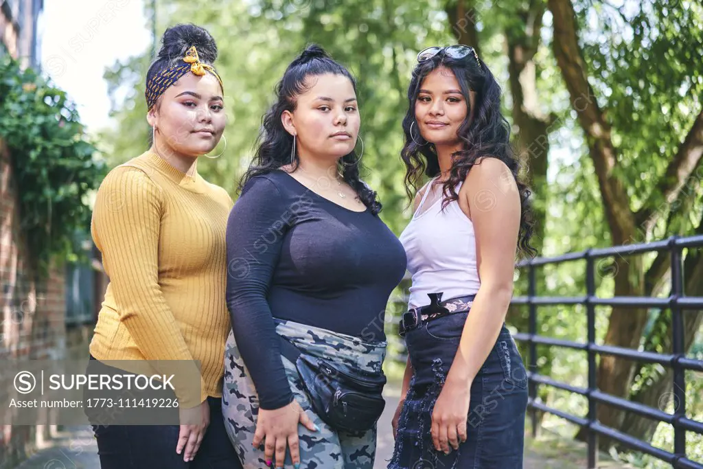 Young woman posing with teenage sisters by park, portrait