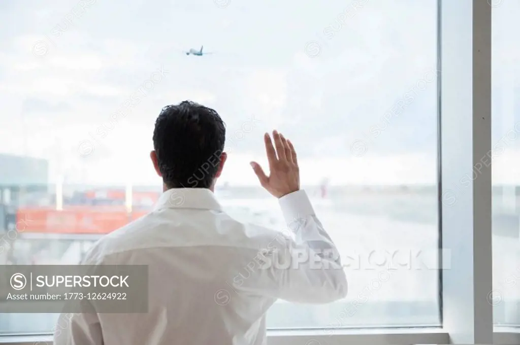 Man at airport window, waving