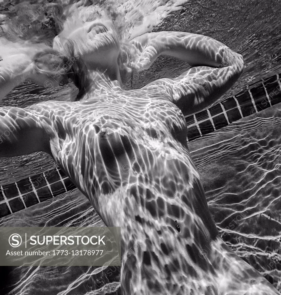 Woman swimming naked underwater - SuperStock