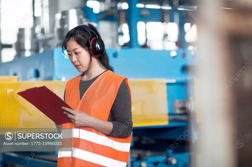 Technician writing on clipboard in factory