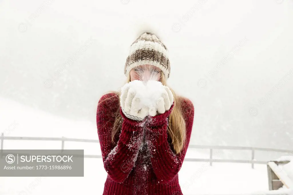 Young woman blowing handful of powder snow