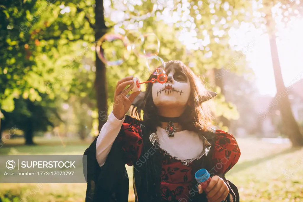 Girl in Halloween costume, blowing bubbles