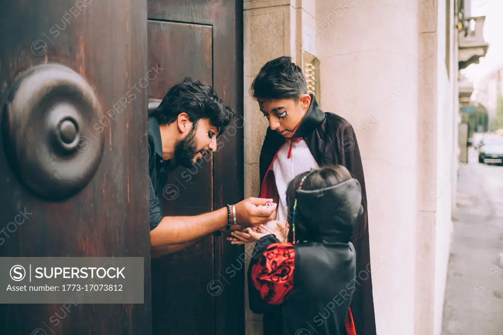 Man giving Halloween candy to children trick or treating 