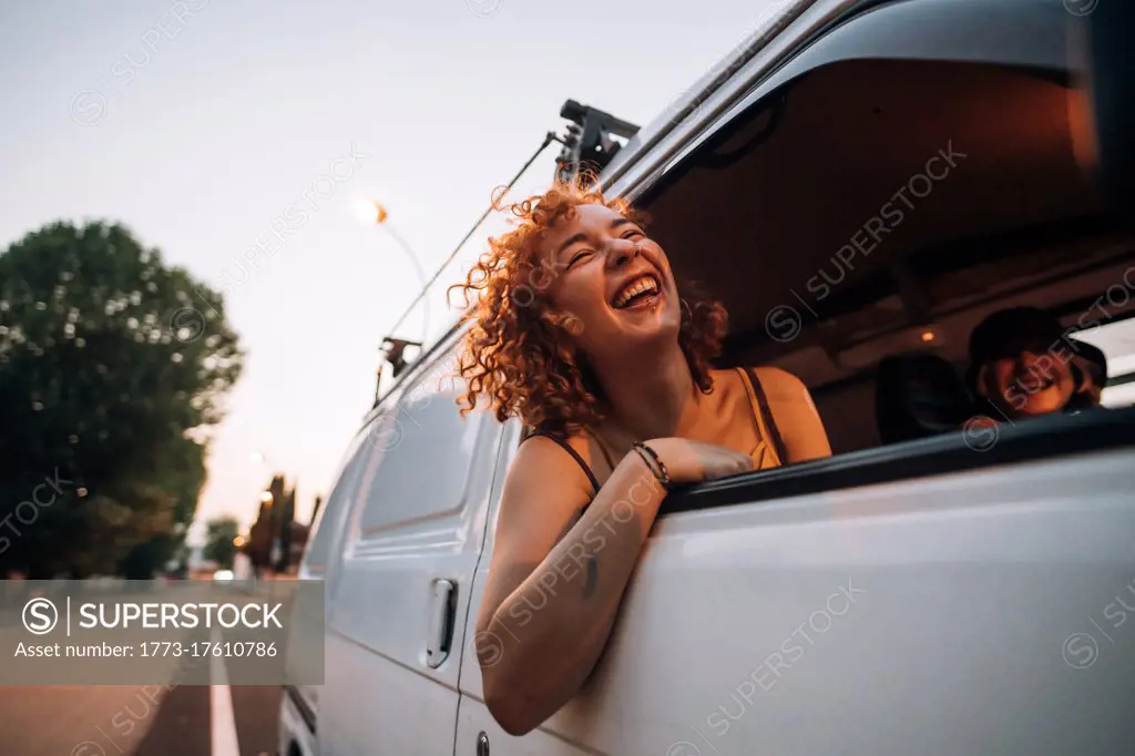 Happy young woman leaning out of van window