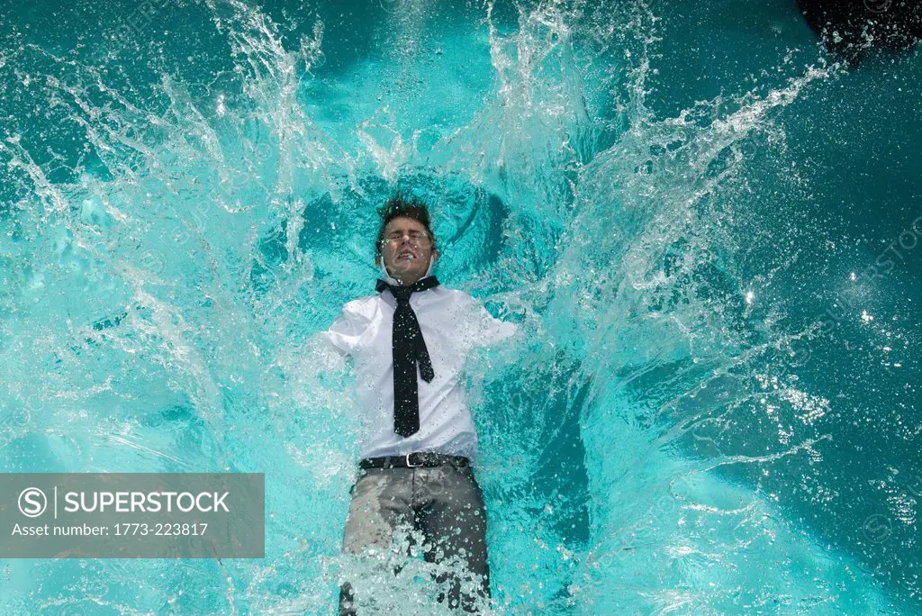 Young man in clothes falling into swimming pool