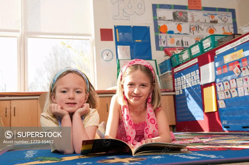 younger student with older student reading together in the classroom