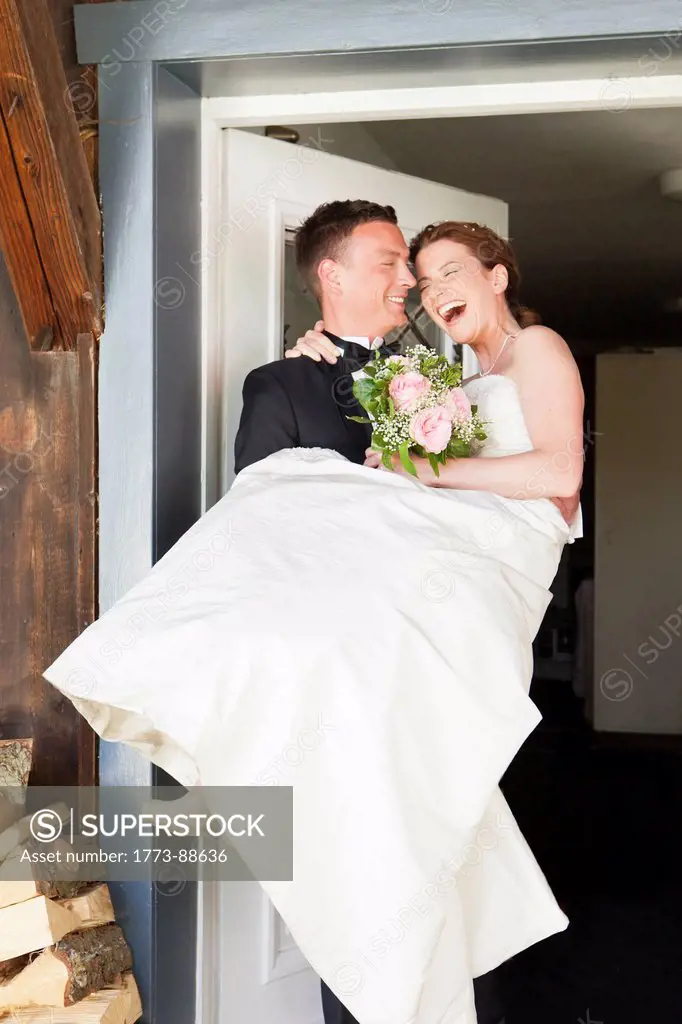 Groom carrying bride across threshold