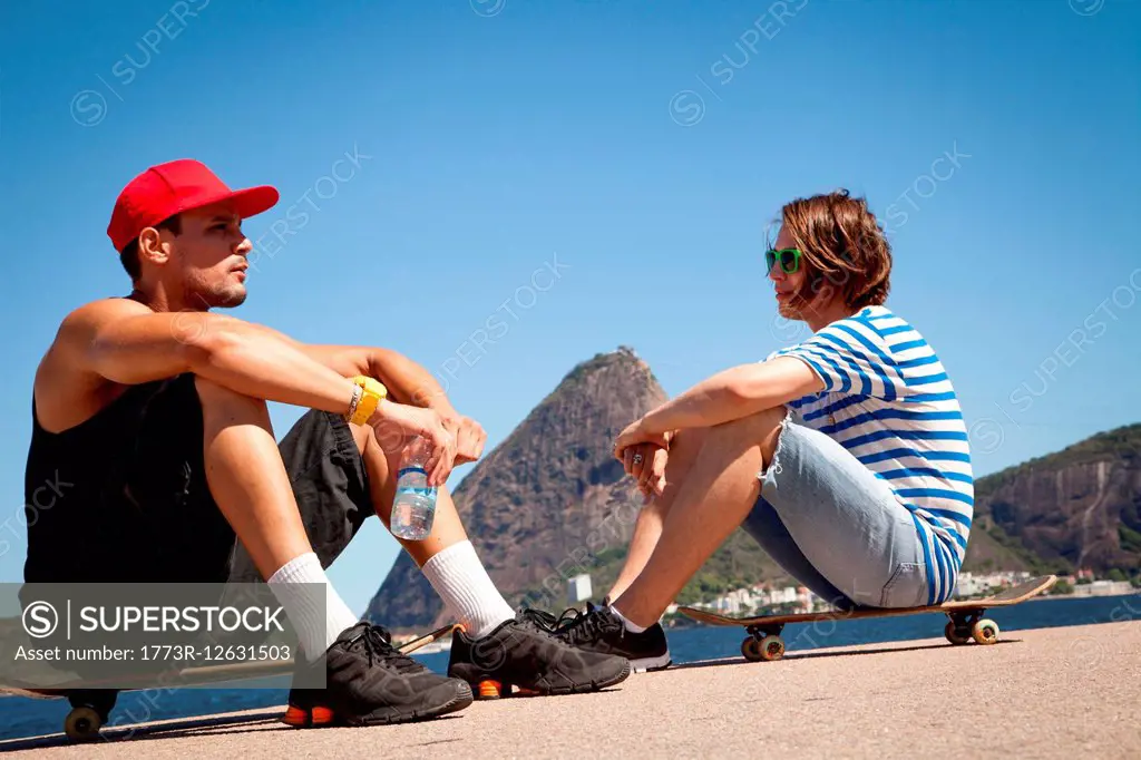 Two men sitting on skateboards, relaxing