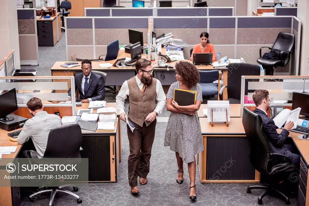 Businesswoman and man walking and talking in office