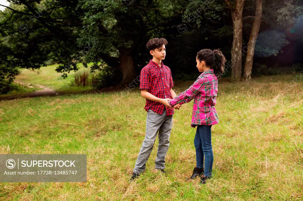 Brother and sister outdoors, holding hands