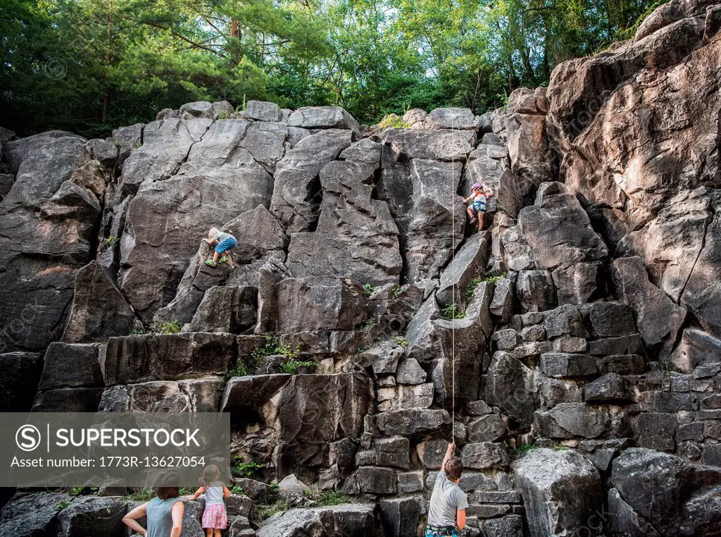 Family rock climbing rock face