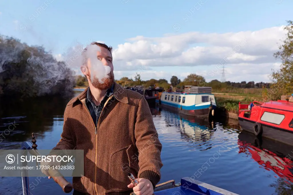 Man smoking e-cigarette on canal boat