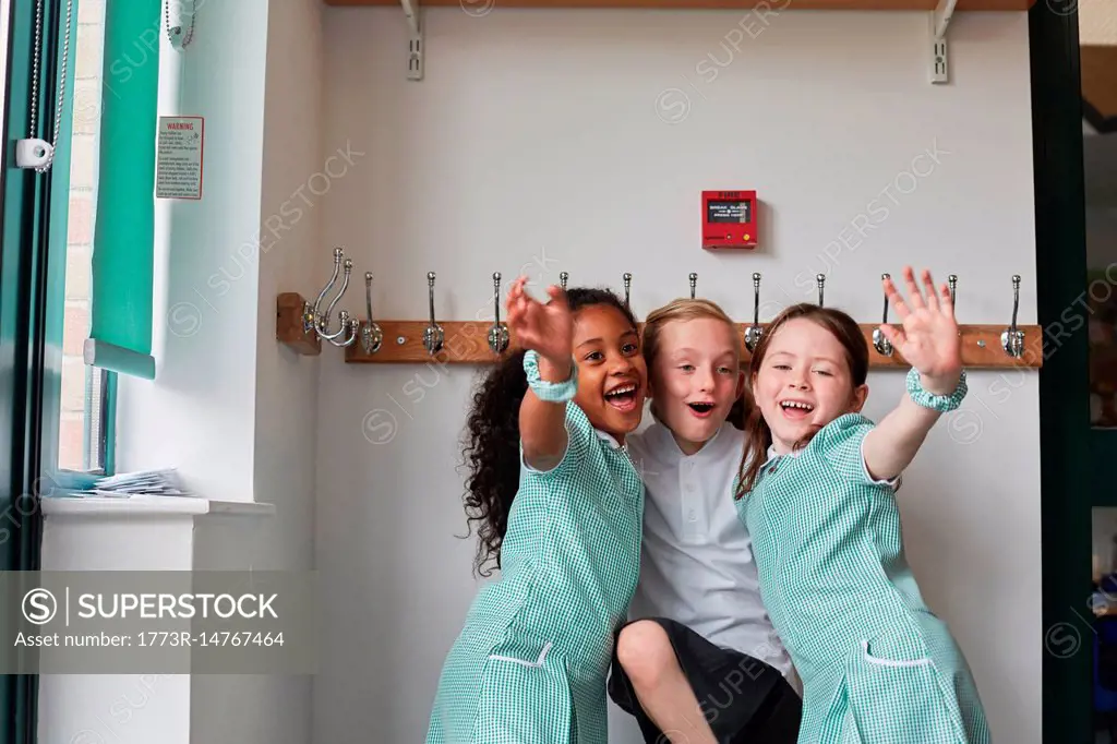 Three schoolgirls having fun in primary school cloakroom