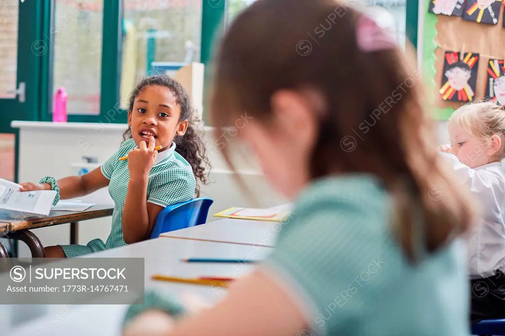 Schoolgirl looking over her shoulder in classroom at primary school