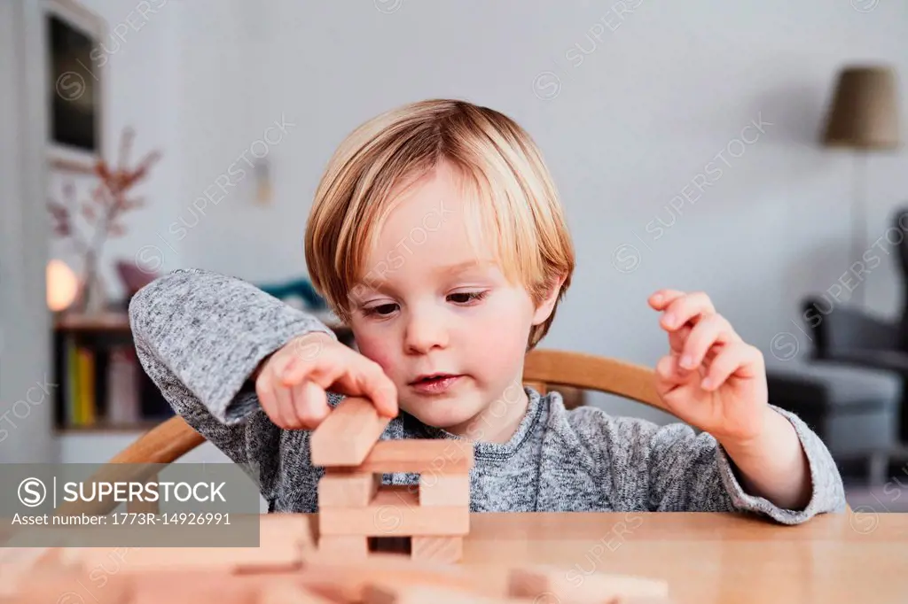 Portrait of young boy, building structure with wooden building blocks