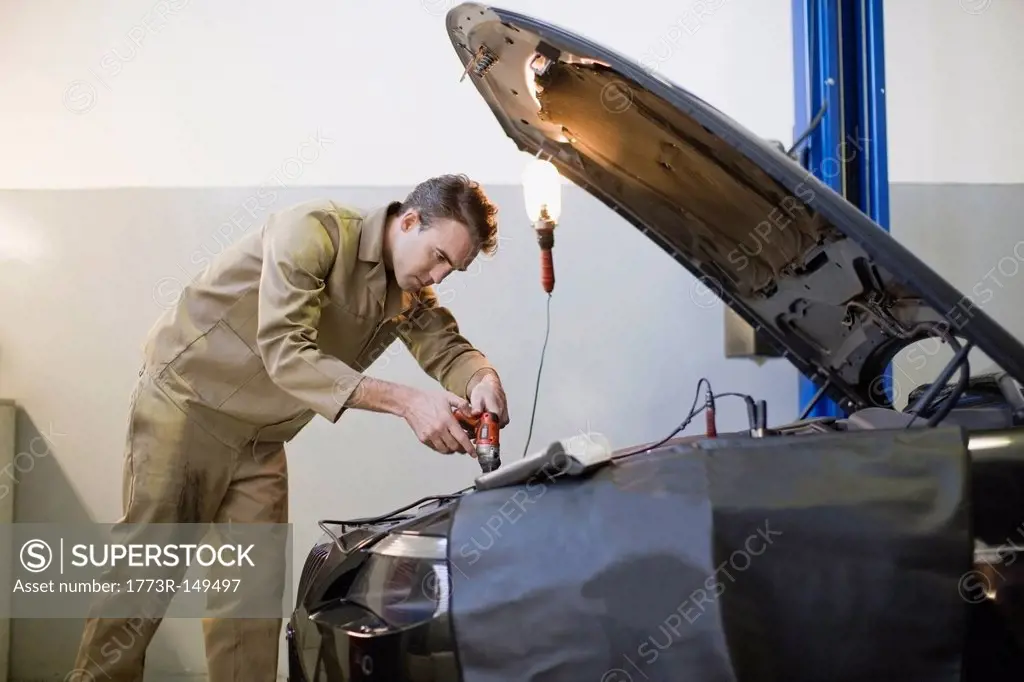 Mechanic working on car engine in garage