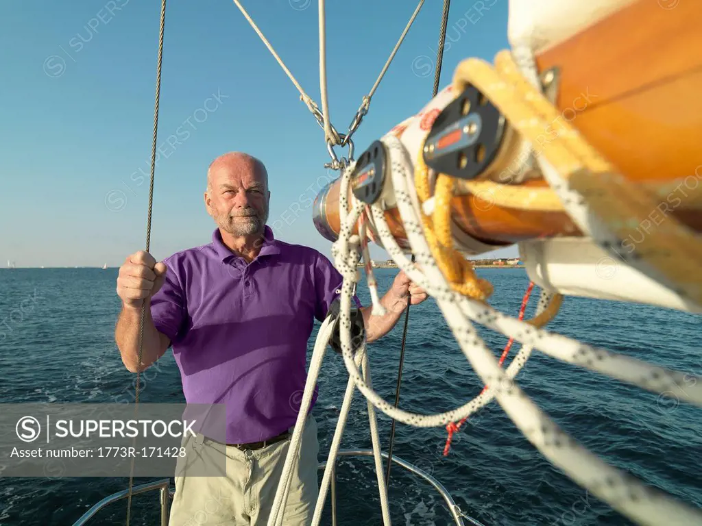 Man adjusting rigging on sailboat