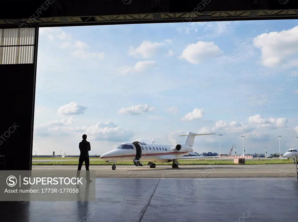 Technician in hangar looking at private jet on tarmac