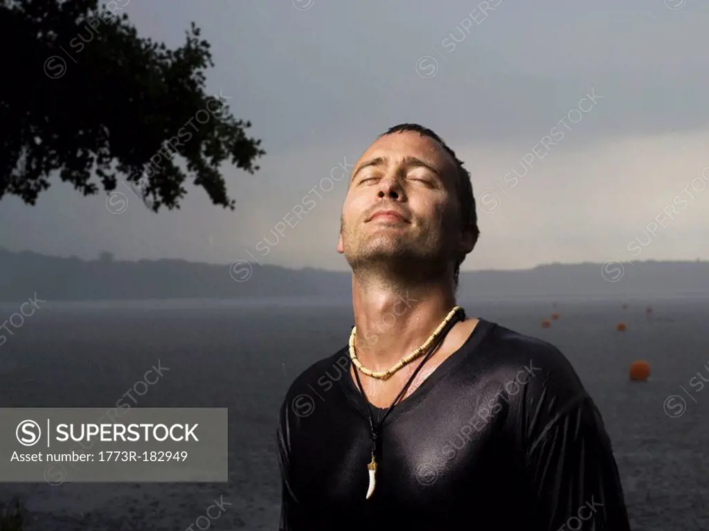 Man standing in rain, eyes closed