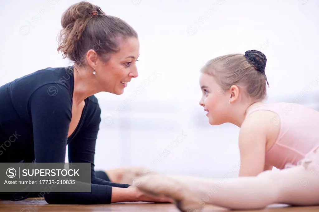 Teacher and young ballerina practicing floor stretch