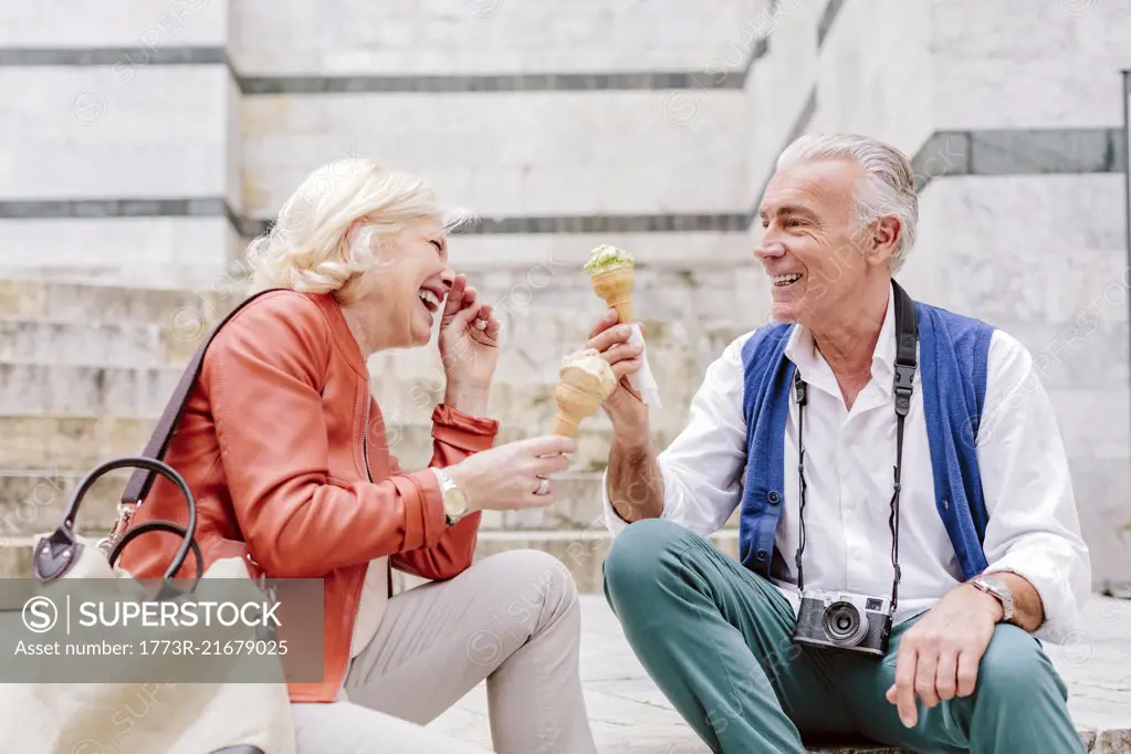 Tourist couple eating ice cream cones and laughing in Siena, Tuscany, Italy