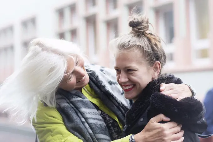 Mature woman and daughter hugging on city street