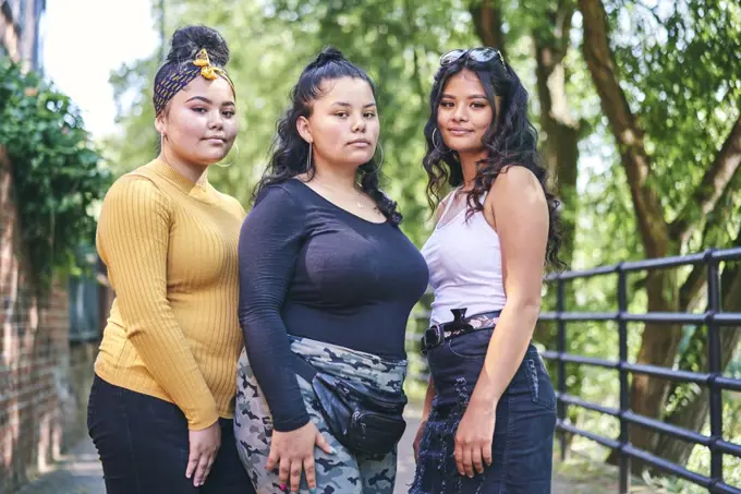 Young woman posing with teenage sisters by park, portrait