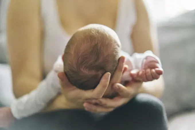 Mother supporting head of baby on lap