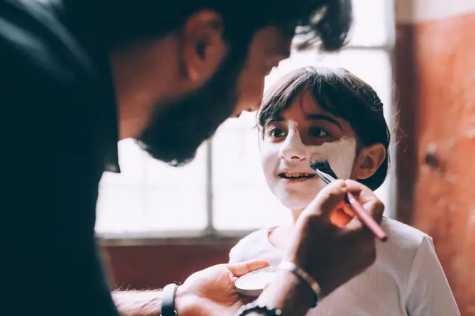 Father painting daughter's face for Halloween