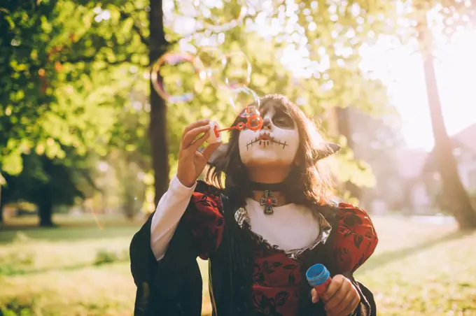 Girl in Halloween costume, blowing bubbles